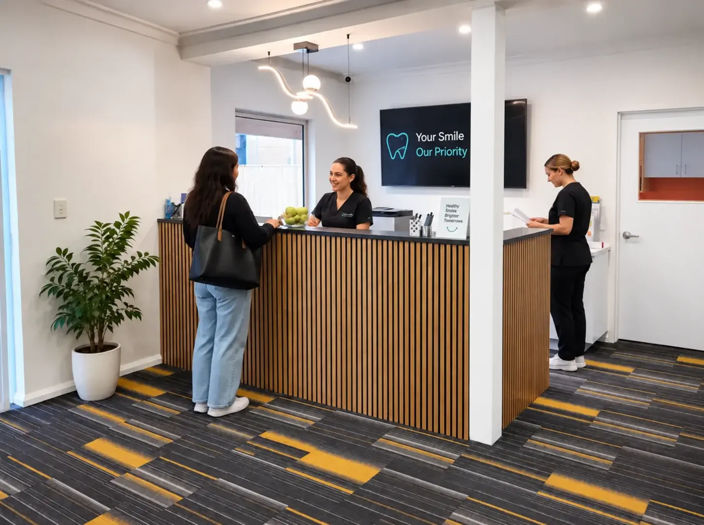 The reception desk at Hocking Dental Care, with two staff members and a visitor at the counter